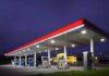 Fuel Fines Hit Gas Stations: Cheats Exposed! A gas station at night with illuminated fuel pumps and a convenience store