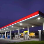 Fuel Fines Hit Gas Stations: Cheats Exposed! A gas station at night with illuminated fuel pumps and a convenience store