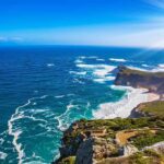 Rocky coastal cliffs with turquoise ocean and bright sun