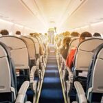 airplane cabin with passengers seated in economy class