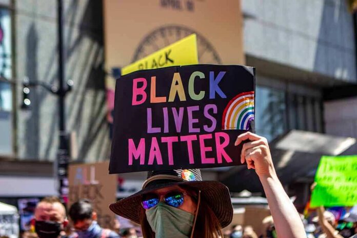 shutterstock_1756811396 protester holds colorful sign at a city street demonstration