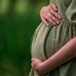 Pregnant woman holding her belly in a green dress