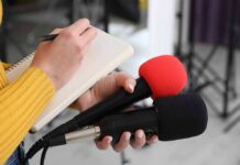 Lindsay Clancy’s Lawyer Turns To Trump With Desperate Plea Journalist holding two microphones while writing in a notebook
