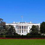 The White House facade with flag and gardens