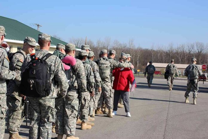 Soldiers in uniform line up outdoors with gear