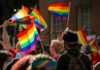 Crowd waving rainbow flags at an outdoor event