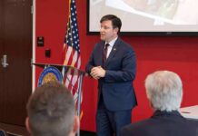 Speaker in a navy suit addressing an audience at a podium