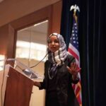 Ilhan Omar speaking at a podium with a microphone