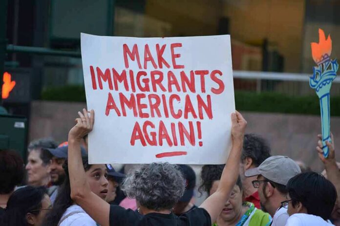 Teddy Williams at a protest holding a sign reading 'Make Immigrants American Again'