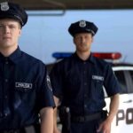 Two police officers standing near a patrol car