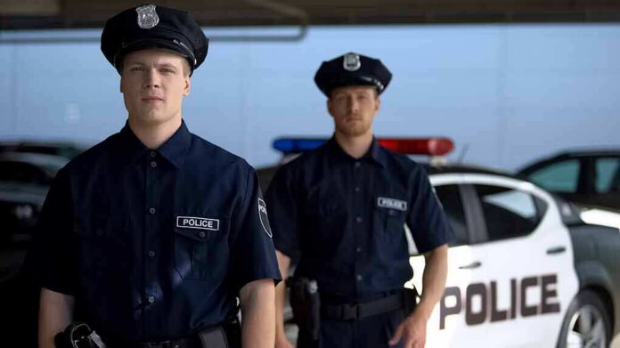shutterstock_1492496696 Two police officers standing near a patrol car