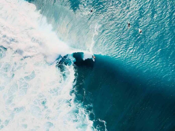 shutterstock_1722733663 Surfer riding a large turquoise wave from above