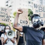 Protester in gas mask raises fist during street demonstration