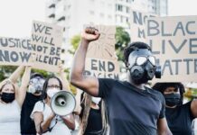 UNHINGED BLM Professor Doxxes ICE Agent Protester in gas mask raises fist during street demonstration