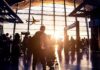 Airport terminal crowd at sunset with airplane silhouette outside