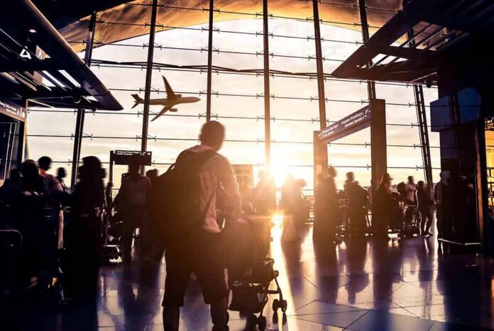 Airport terminal crowd at sunset with airplane silhouette outside