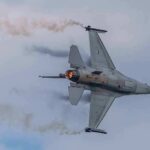 Fighter jet banking with afterburner against a cloudy sky