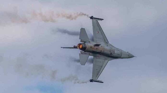 Fighter jet banking with afterburner against a cloudy sky