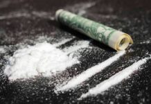 White powder and rolled bill on a dark surface