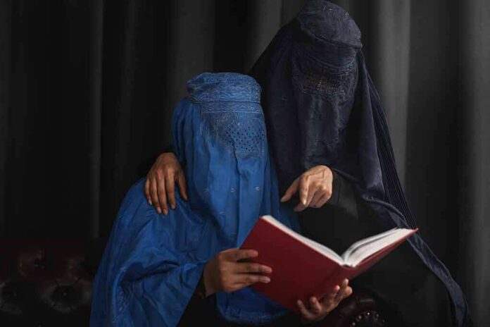 shutterstock_2225515413 Two veiled women reading a red book together