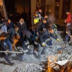 Rescue workers dig through rubble at night
