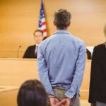 Defendant in handcuffs standing before a judge in a courtroom