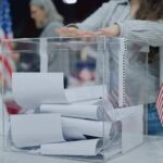 Red-State REWRITES It’s Constitution – New Amendment Passed! Person casting a ballot into a clear box at a polling station