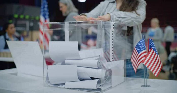 Person casting a ballot into a clear box at a polling station