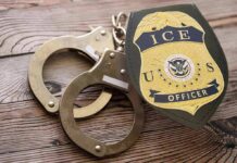 ICE officer badge and handcuffs on wooden surface