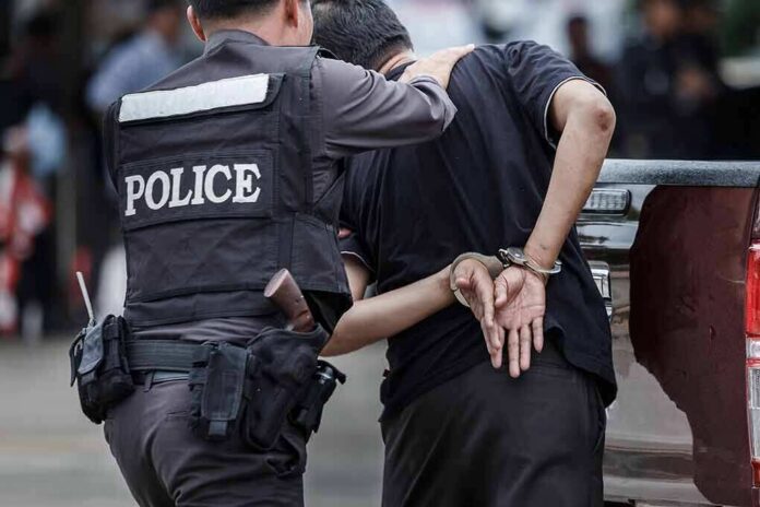 Police officer escorting handcuffed man to a vehicle