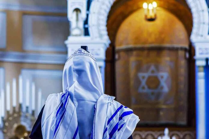 shutterstock_709900843 Person in white and blue prayer shawl facing ornate interior