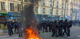 Fire burning on the street amid police presence.