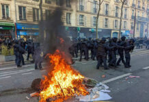 Fire burning on the street amid police presence.