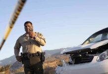 Police officer at crash scene near damaged white car