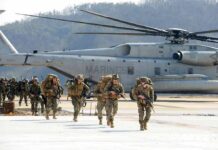 Curfew Imposed on US Bases After Marine Arrested Soldiers disembark and walk past a large military helicopter