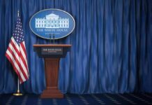 Trump Announces NEW Press Sec, And She Comes With A LOT Of Baggage White House press briefing podium with U.S. flag and blue curtain