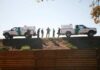 Border patrol agents stand between two marked trucks on an embankment