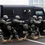 Tactical team advances beside an armored vehicle