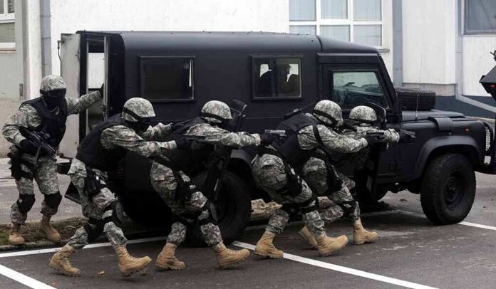 shutterstock_135978617 Tactical team advances beside an armored vehicle