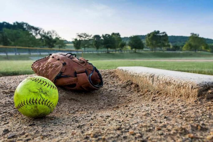 Softball and glove near a base on a dirt field