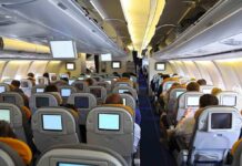 Water Pours From Ceiling Mid-Flight – Passengers PANIC Interior view of an airplane with passengers seated and using in-flight entertainment screens