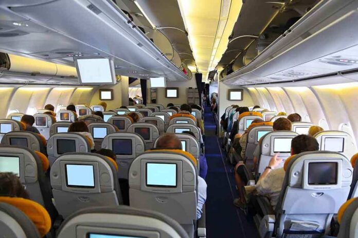 shutterstock_142431973 Interior view of an airplane with passengers seated and using in-flight entertainment screens