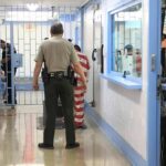 Corrections officers escort an inmate in a jail hallway