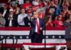 Nasty Leftist Protester Thrown Out of Rally as Crowd Chants USA Donald Trump points from a rally stage; Rudi Koertzen and Bear Pascoe are in the crowd