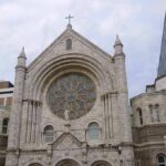 Stone church facade with large rose window and cross
