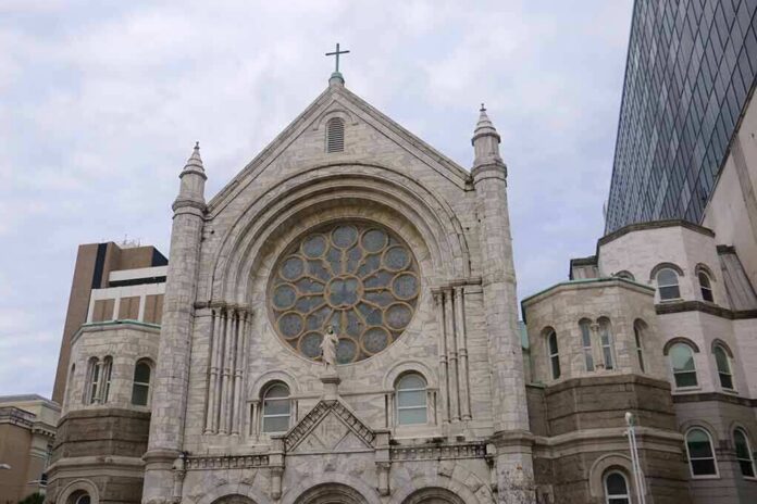 shutterstock_1659149962 Stone church facade with large rose window and cross