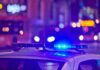 Jammed Rifle Halts Chilling Temple Plot police car roof with flashing blue lights at night