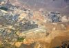 Missiles Rock Airport – 12 DEAD! Aerial view of desert city with airport and highways