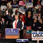 Donald Trump addresses a rally crowd at a podium, raising his fist